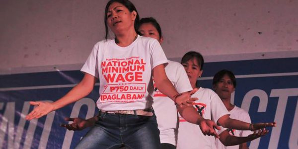 Workers gesture in a performance to demand a national minimum wage